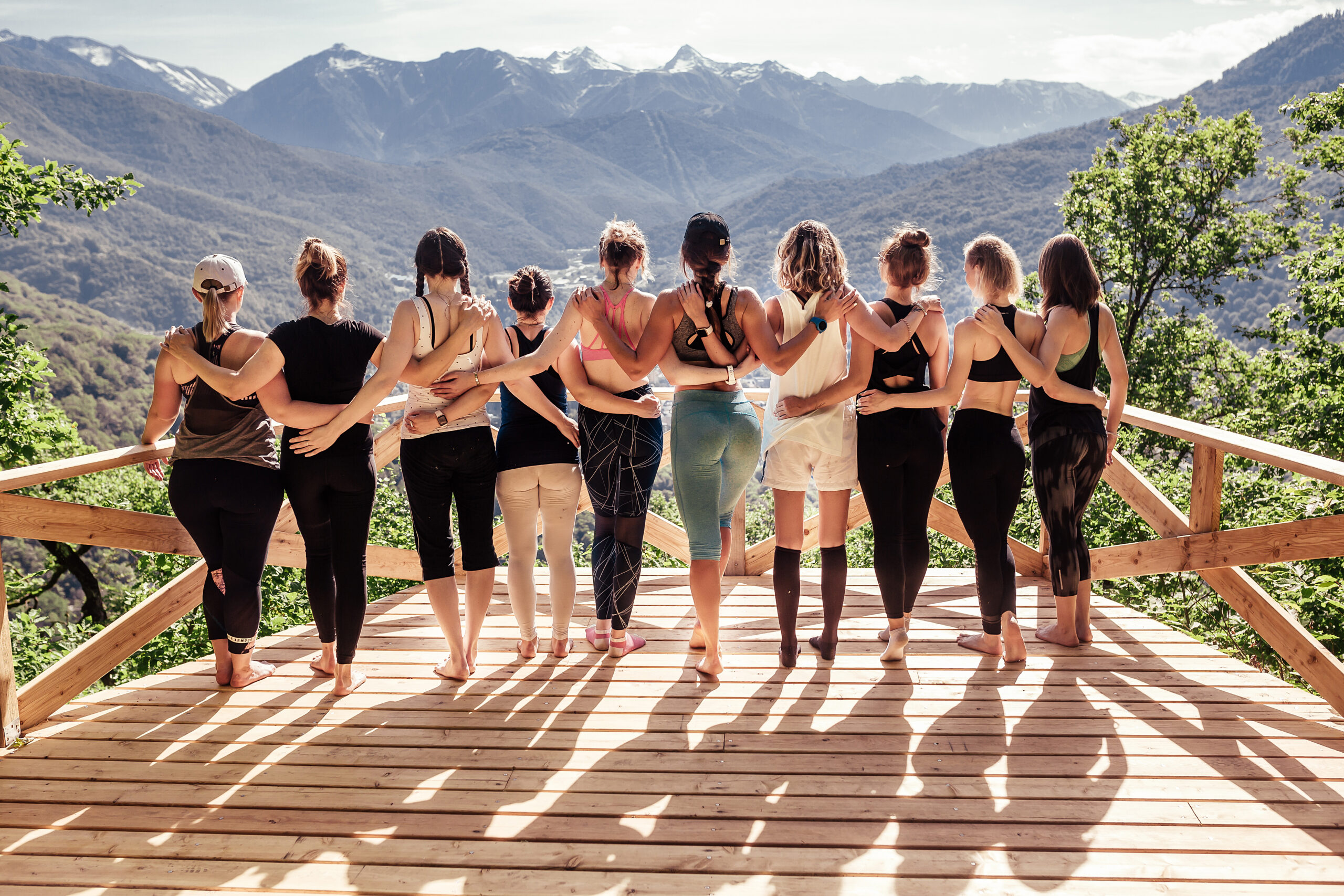 Rear view of a group of slim body-positive sportive active friendly women doing fitness and yoga together among mountain ecologically clean nature. Ecological Sports Tourism Concept